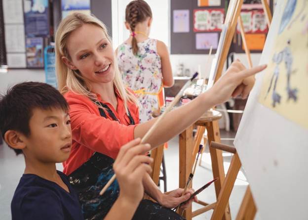 elementary art teacher works with student