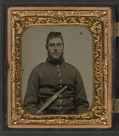 man in uniform with large thin knife in belt at waist